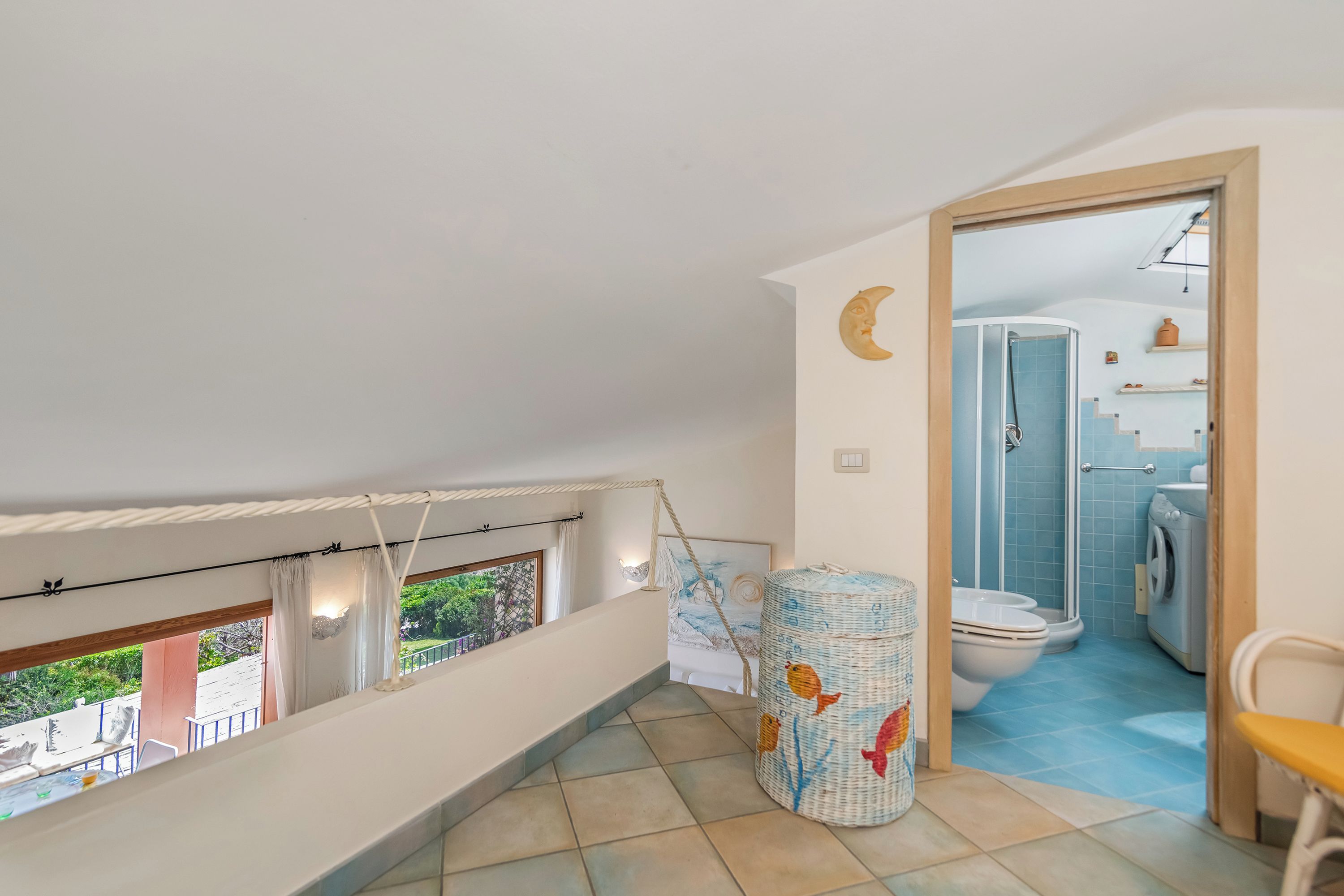 Un balcon avec vue, un panier en osier, des toilettes et un lave-linge dans la pièce adjacente.