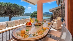 A dining area with a table set for four, overlooking a scenic view of the sea and mountains. - Casa Titta (Olbia)
