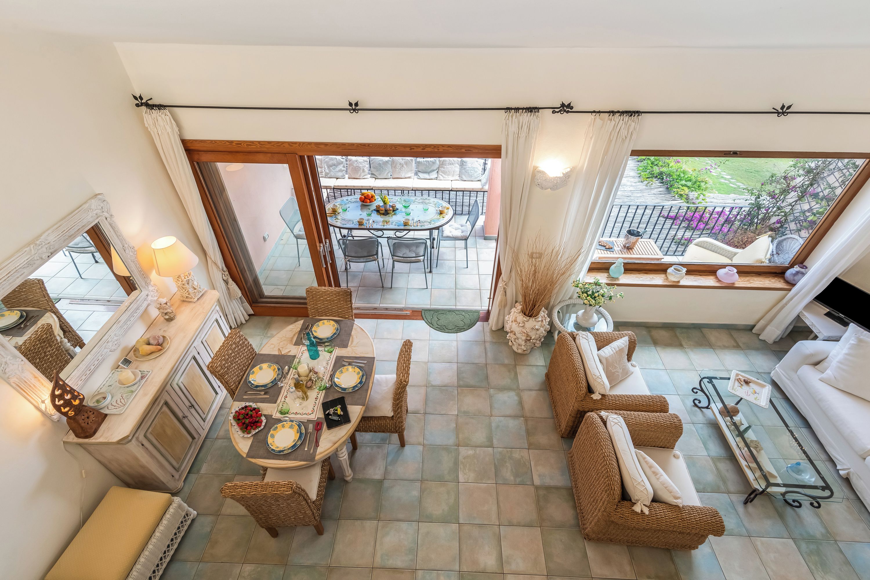 A dining area with a table set for four, a sofa, and a balcony with a view.
