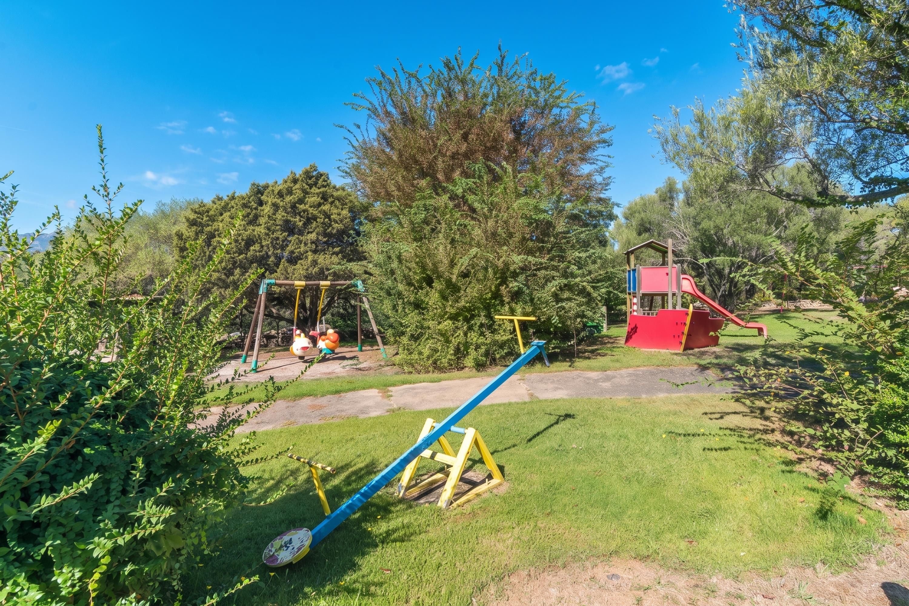 A playground with swings, a seesaw, and a slide.