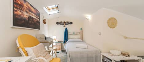 A room with a bed, a desk, a chair, a wall-mounted shelf, and a painting.