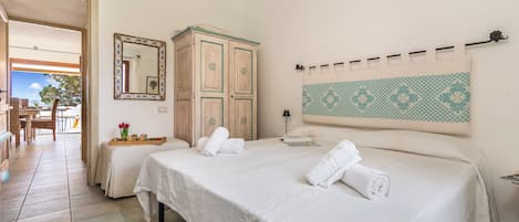 Une chambre d’hôtel avec deux lits, une armoire en bois, un miroir, une décoration murale à motifs et une vue sur l’extérieur.