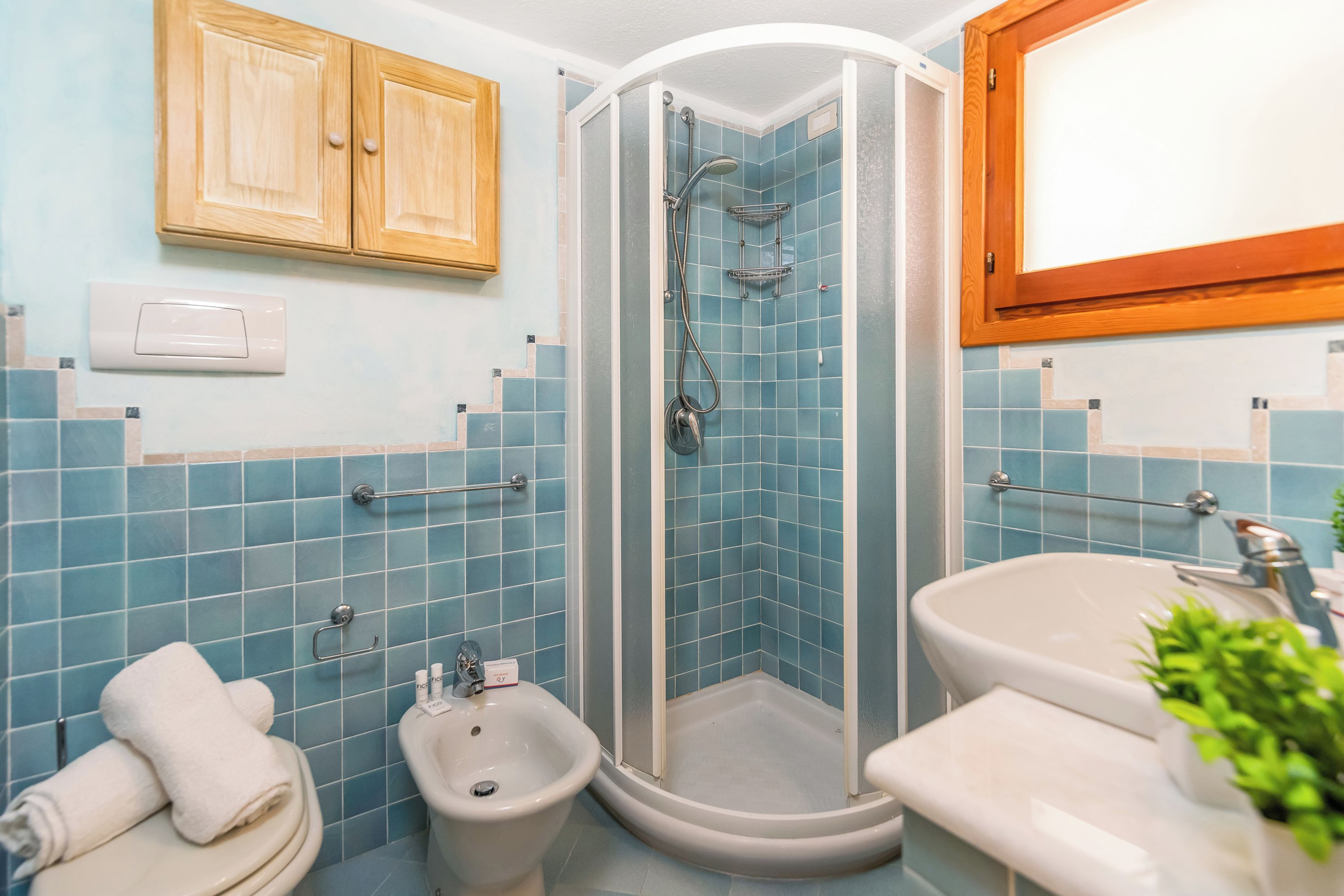 A bathroom with a shower, bidet, sink, and toilet.