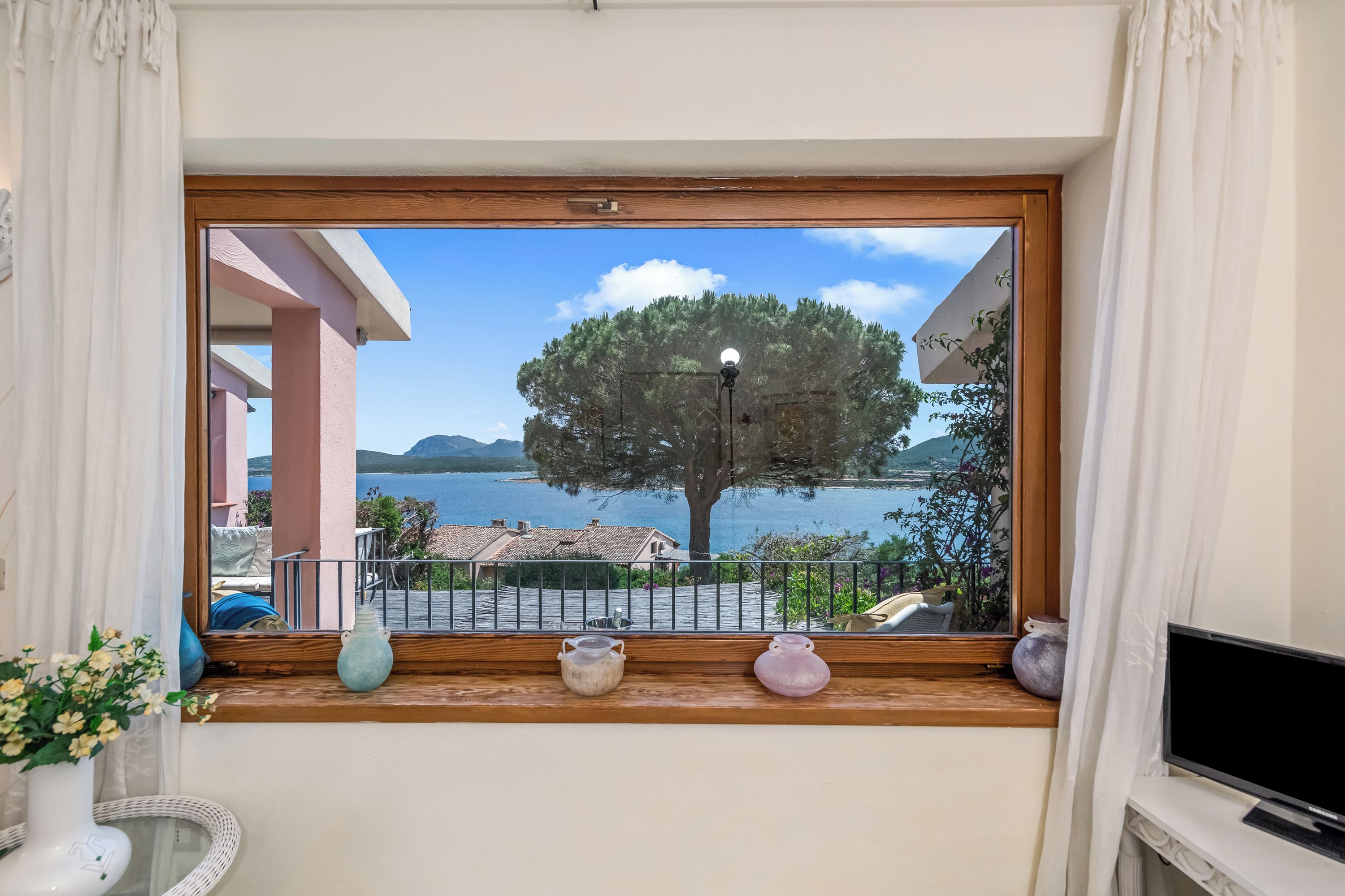 Un balcón con vista a un lago, un árbol y una montaña al fondo.
