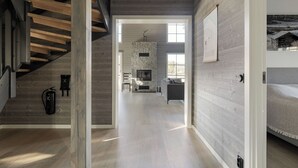 Ein modernes Interieur mit Treppe, Kamin aus Stein und Wohnbereich mit Sofa und Fernseher.