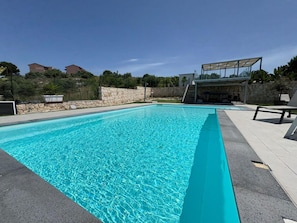 A rectangular swimming pool with clear blue water, surrounded by a stone wall and a paved deck. - Rari House by Geco Vacation Rentals (Brucoli)