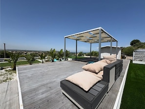 A wooden deck with a covered seating area and a view of the landscape. - Rari House by Geco Vacation Rentals (Brucoli)