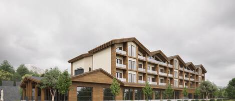 A multi-story hotel with a modern architectural design, featuring balconies and a landscaped front yard.