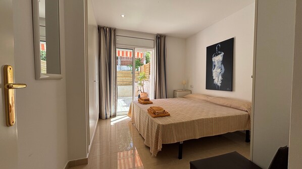 Une chambre dâhĂŽtel avec un lit, une table de chevet, un tableau et une vue sur lâextĂ©rieur, visible Ă travers la porte.