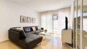 A modern living room with a black leather sofa, a white coffee table, and a TV stand. - Apartment 'Brisas Del Mar Pb-3' with Shared Pool, Wi-Fi and Air Conditioning (Torroella de Montgrí)