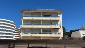 Un immeuble Ă plusieurs Ă©tages, dotĂ© de balcons et dâun toit plat, se dressant sous un ciel bleu azur.
