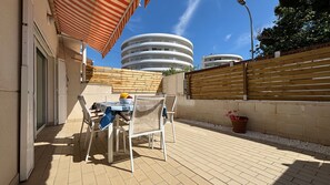 Une terrasse avec une table et des chaises, une clĂŽture en bois et, au fond, un bĂątiment moderne.