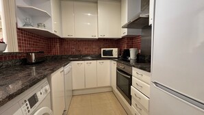 A kitchen with white cabinets, a microwave, a coffee maker, and a dishwasher. - Apartment 'Brisas Del Mar Pb-3' with Shared Pool, Wi-Fi and Air Conditioning (Torroella de Montgrí)