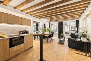 Eine moderne Küche mit Holzschränken, einer Marmorarbeitsplatte und einem Essbereich mit rundem Tisch und Stühlen.