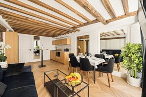 A spacious living area with a dining table, black chairs, a sofa, and a coffee table with fruit. - 2BDR/5P apartment au centre de Paris in downtown Paris (Paris)