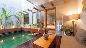 Un intérieur moderne avec une piscine en bois, un canapé, une lampe et un vase contenant des plantes séchées.