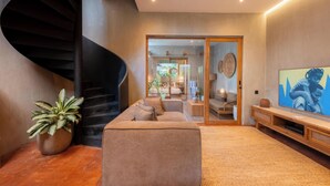 Un intérieur moderne avec un escalier en colimaçon, un canapé, un téléviseur et une plante en pot.