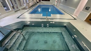 Une piscine intérieure avec un panneau indiquant « ZONE PEU PROFONDE », un espace séparé avec un bain à remous et un panneau « FEMMES » sur le mur.
