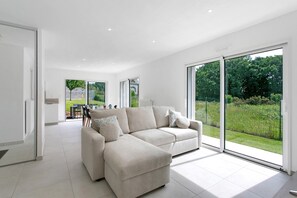 A modern living room with a sectional sofa, large sliding glass doors, and a view of a garden.