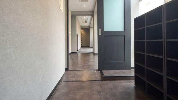 A hallway with a dark door, a tiled floor, and a view into another room. - Guesthouse Akasaka2 (Tokyo)