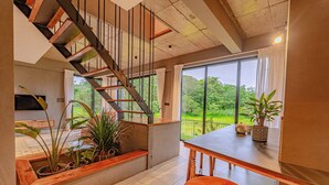 Un intérieur moderne avec un escalier, un coin repas et une vue sur la verdure.