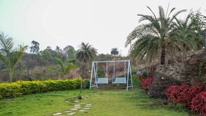 A garden with a swing set, stone pathway, and various plants. - Bellajooz Lake Resort (Mawal)