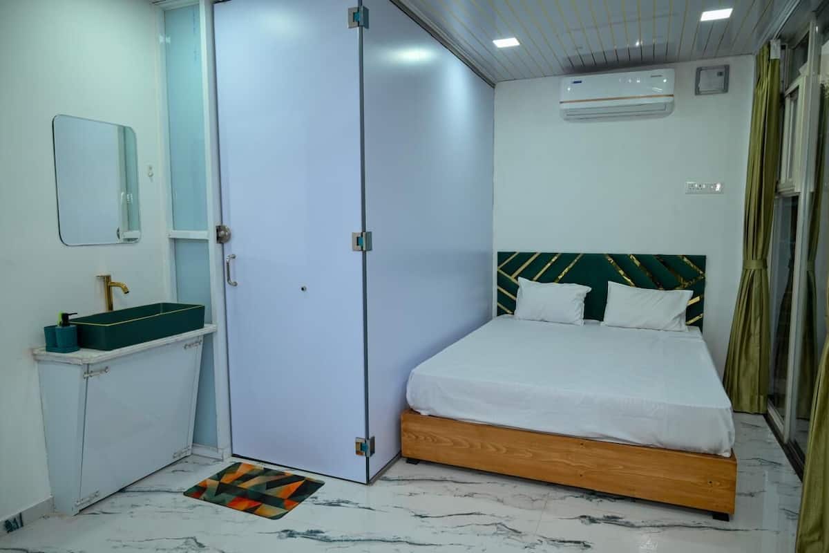 Un dormitorio con cama, armario, lavabo y espejo.
