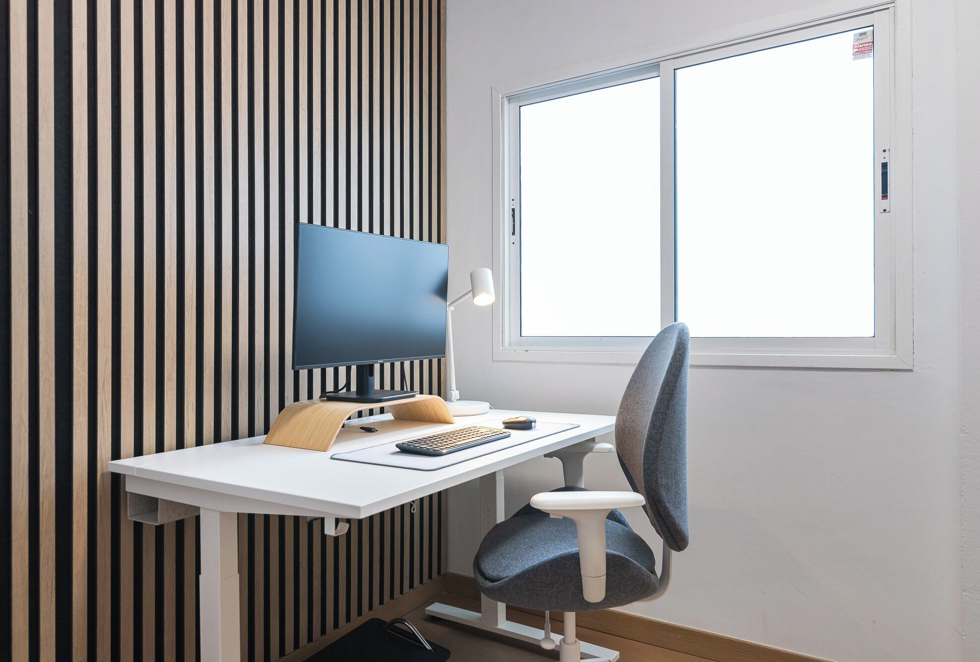 A workspace with a computer, desk, chair, and a window withered window.