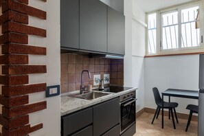 Eine kleine Küche mit Backofen, Spüle und einem Fenster mit Gitterstäben.