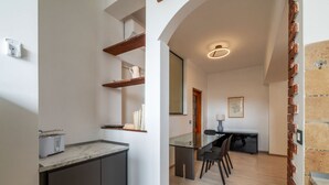 Una cocina moderna con encimera de mármol, estanterías empotradas y un comedor con mesa y sillas de vidrio.