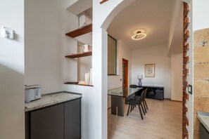 Eine moderne Küche mit Marmorarbeitsplatte, eingebauten Regalen und einem Essbereich mit Glastisch und Stühlen.