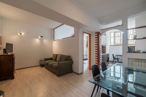 Ein geräumiger Wohnbereich mit einem Glastisch, einem grünen Sofa und einem Holzkasten.