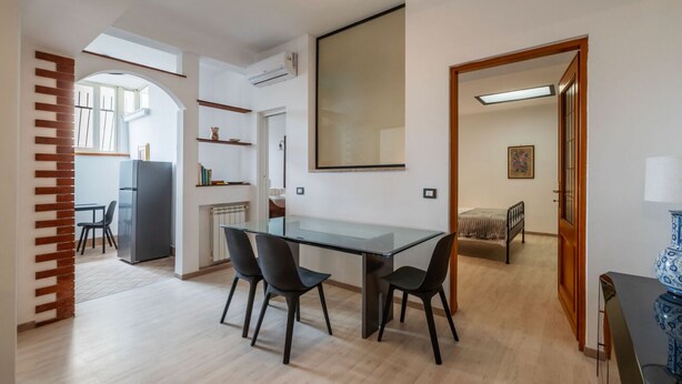 Una cocina moderna con una mesa y sillas de vidrio, un refrigerador y un ventanal grande.