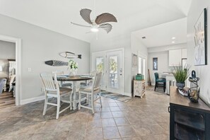 Eine geräumige Küche mit Essbereich, Deckenventilator und Blick durch die Glastüren.