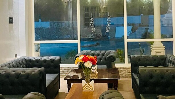 A living room with a large window, a chandelier, and a coffee table with a vase of flowers.