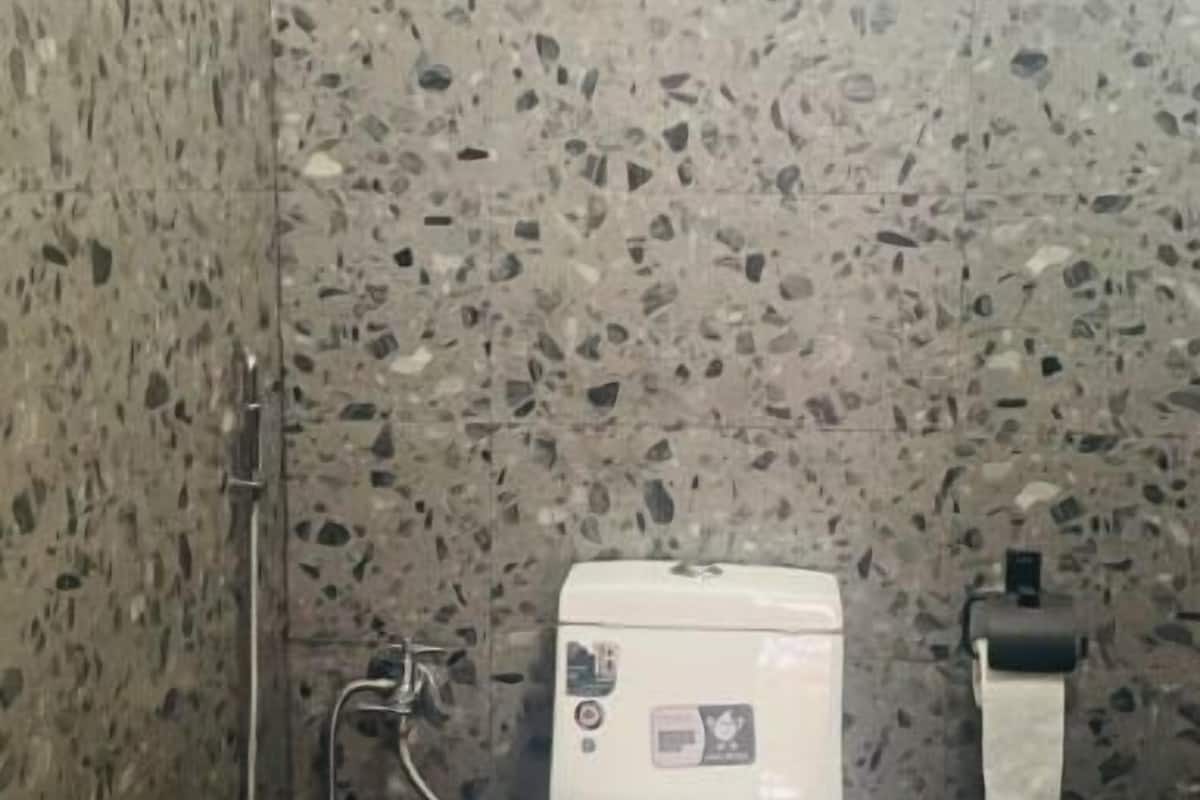 Kylpyhuone, jossa on valkoinen wc-istuin, suihku ja musta roskakori.