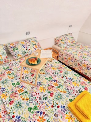 Ein gemütliches Zimmer mit einem Bett, einem Sessel, einem kleinen Tisch mit Tablett und einem Kopfkissen.