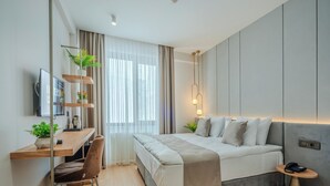 A modern bedroom with a bed, bedside table, desk, chair, and a TV. - Haveria Suite Hotel (Istanbul)