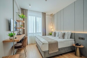 A modern bedroom with a bed, bedside table, desk, chair, and a TV. - Haveria Suite Hotel (Istanbul)