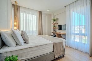 Ein modernes Schlafzimmer mit einem großen Bett, einem Fernseher, einer Pflanze und Balkonblick.