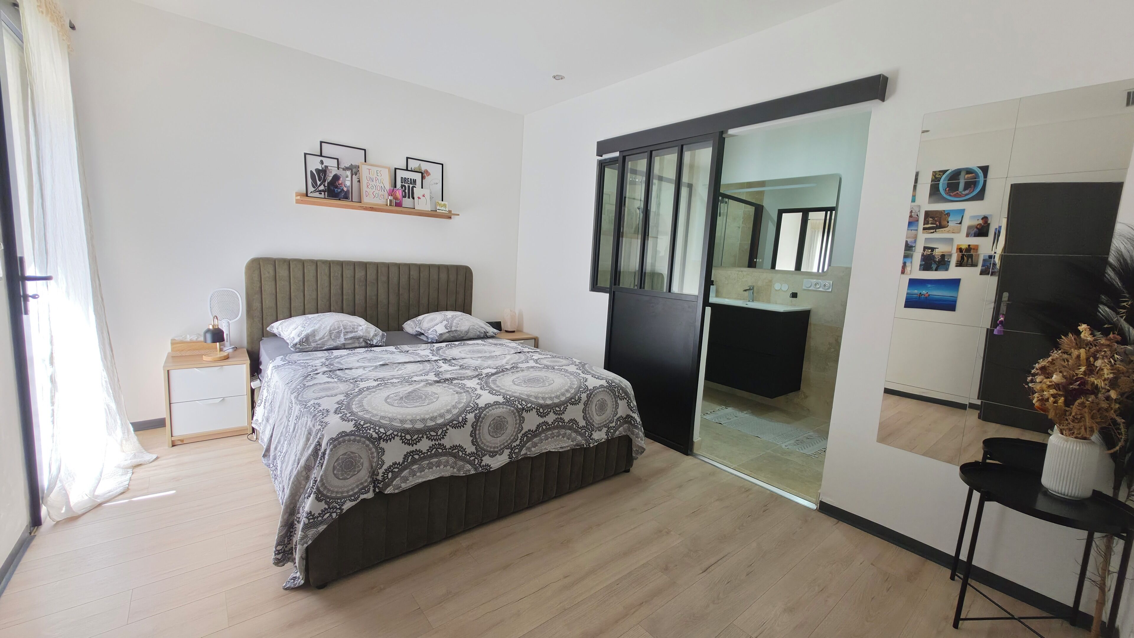 Une chambre à coucher avec un lit, une table de chevet et un miroir.