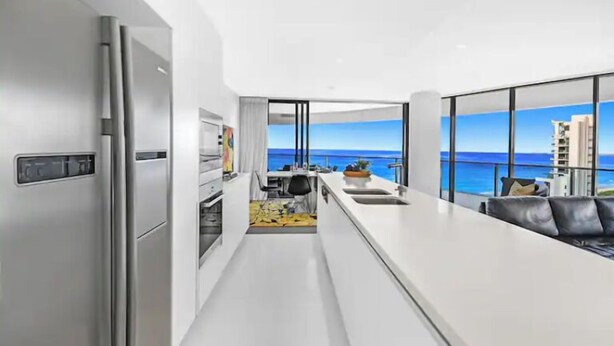 Een moderne keuken met uitzicht op de oceaan, een eethoek en een woonruimte met een bank.