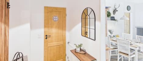 A wooden door with a 'Toilette' sign, a mirror, a white dresser, and a dining area with chairs and a table.