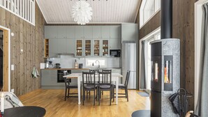 A modern kitchen with grey cabinets, a central island, and a wood-burning stove. - Orrmötesvägen 21 - Funäsdalen (Funäsdalen)