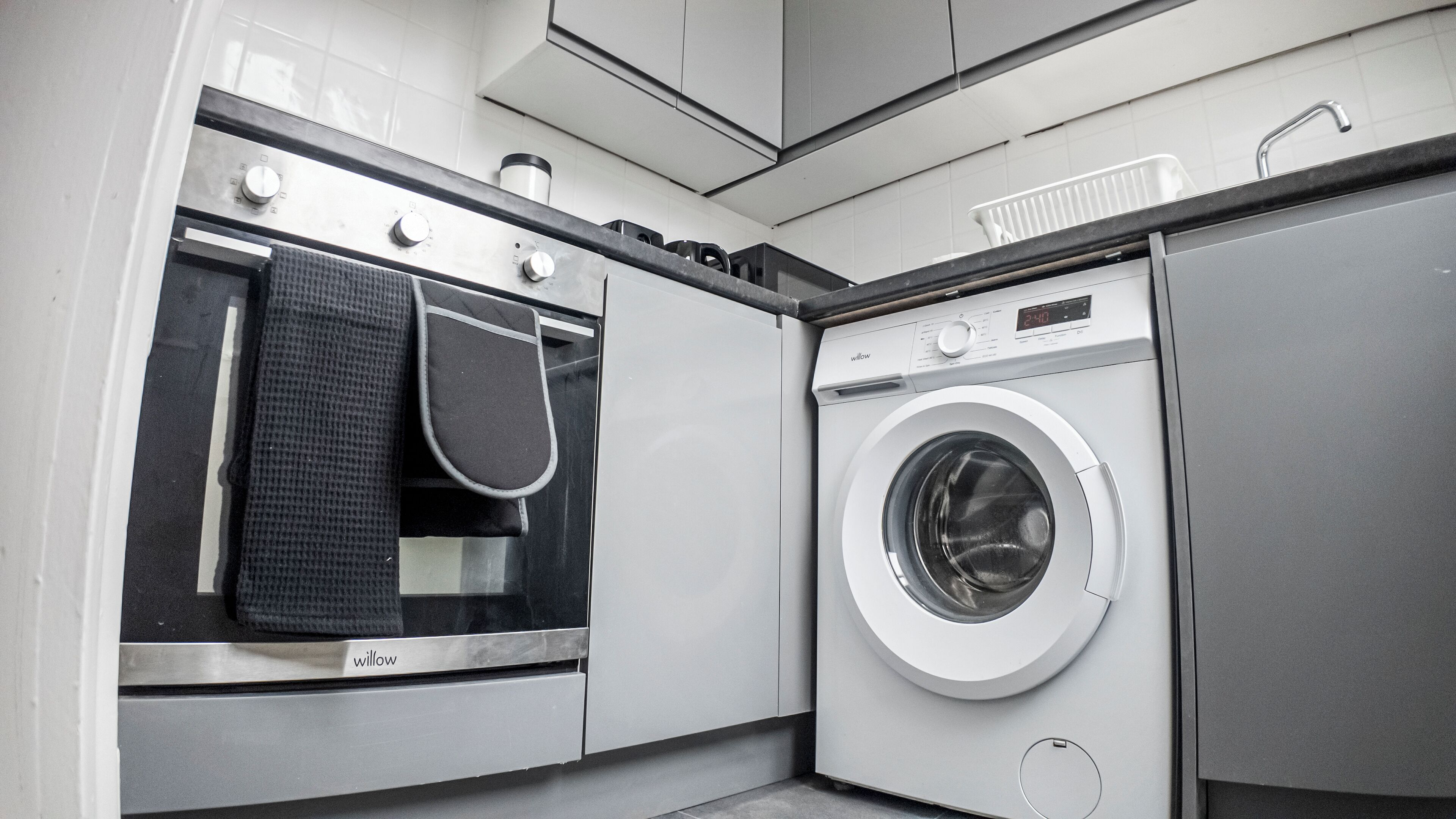 A modern laundry room with a washing machine, a dryer, and a built-in oven.