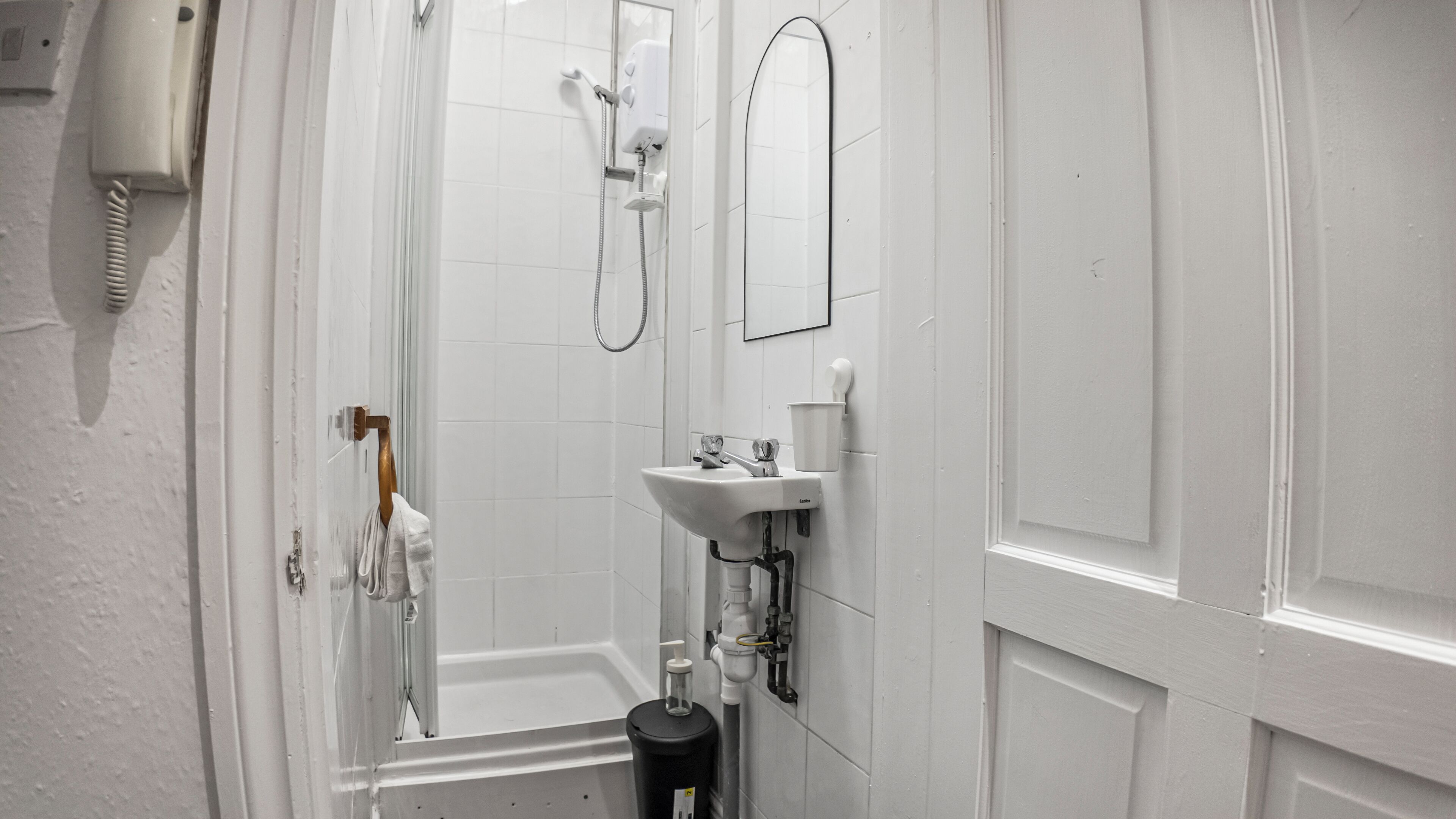 A bathroom with a white sink, a mirror, a shower, and a toilet.