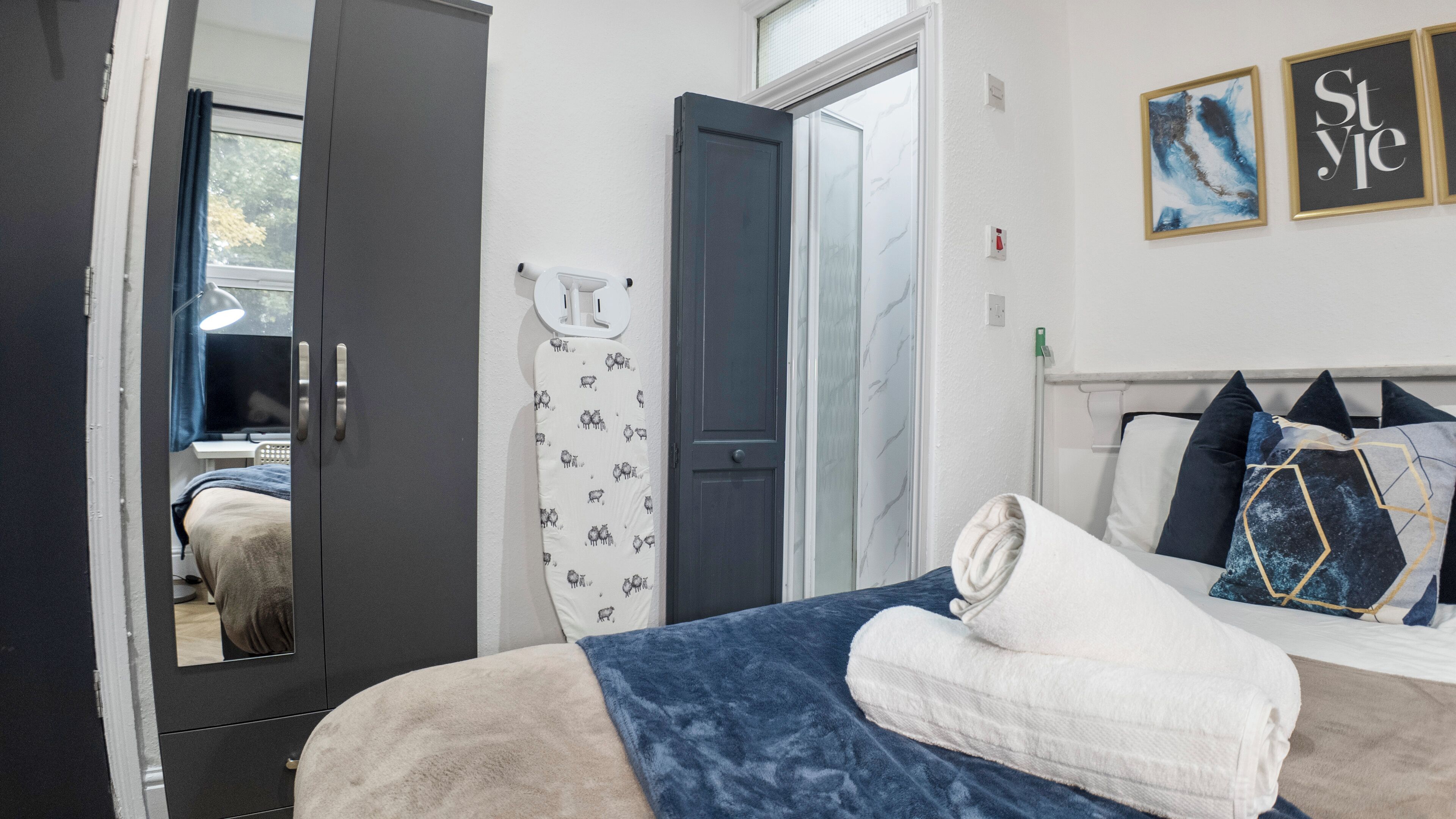 A bedroom with a bed, a wardrobe, a door, and a wall with a framed picture.