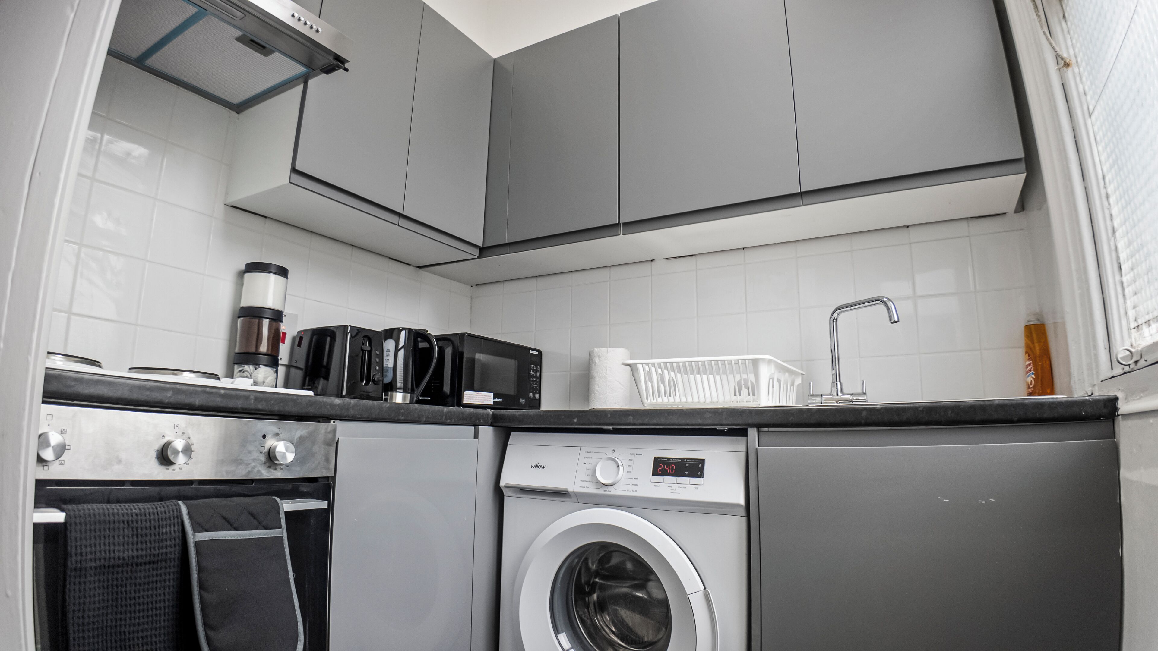 A compact kitchen with a washing machine, microwave, and coffee maker.