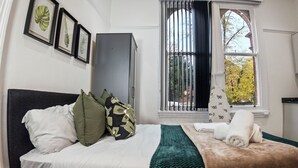 A bedroom with a bed, pillows, a blanket, a wardrobe, and a window with a view. - Modern Retreat in Birmingham (Birmingham)