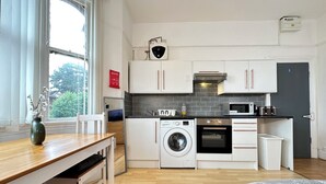 Eine kleine Küche mit Waschmaschine, Mikrowelle und Backofen.